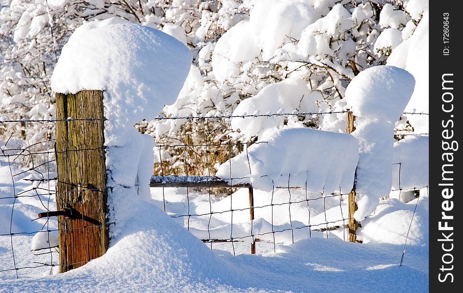 A horizontal image of snow drifts and snow covered fences in bright sunlight. A horizontal image of snow drifts and snow covered fences in bright sunlight