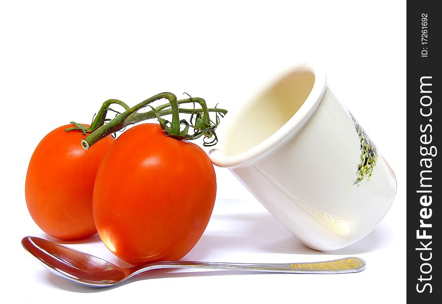 Two Tomatoes lying against a pot with a spoon at the bottom. Isolated on a white background. Two Tomatoes lying against a pot with a spoon at the bottom. Isolated on a white background