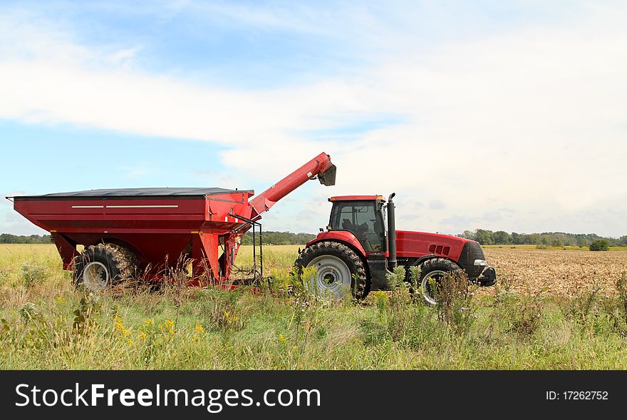 Red farm tractor and wagon in a farm field