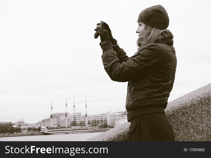 A girl takes pictures a city, upright on the embankment of the river