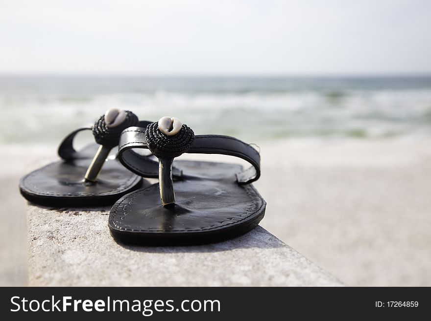 Black flip flops with shells on the beach. Black flip flops with shells on the beach