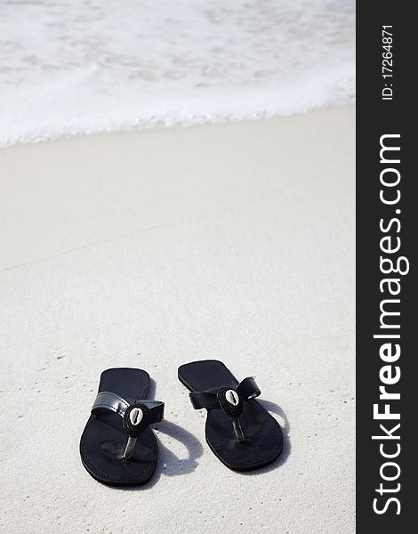 Black flip flops with shells on the beach. Black flip flops with shells on the beach