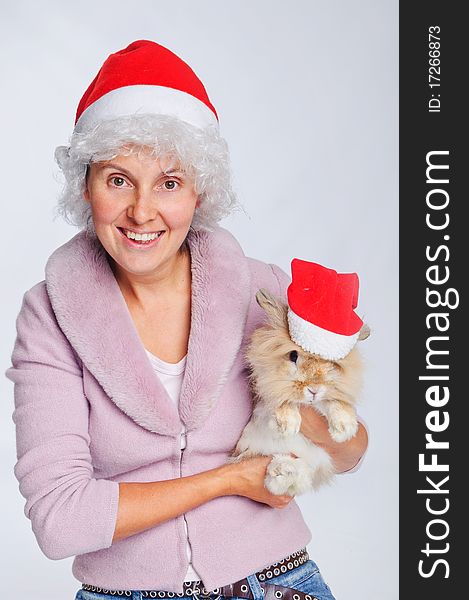 Pretty young woman in Santa hat holding cute rabbit
