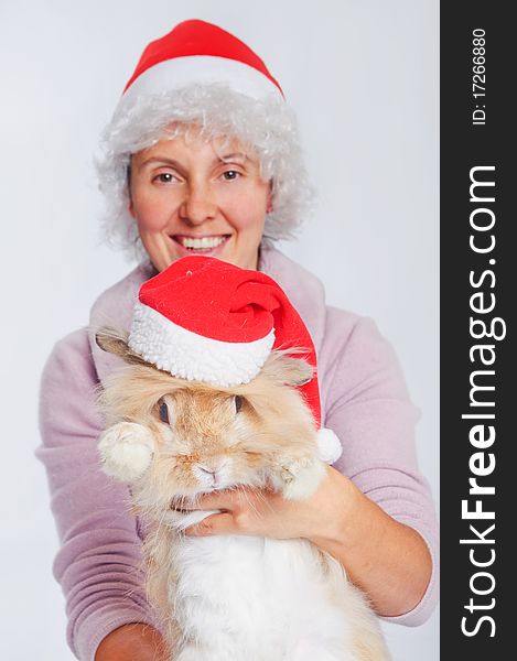 Pretty young woman in Santa hat holding cute rabbit. Focus on the rabbit.