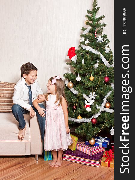 Merry girl and boy with gifts near a new-year tree. Merry girl and boy with gifts near a new-year tree