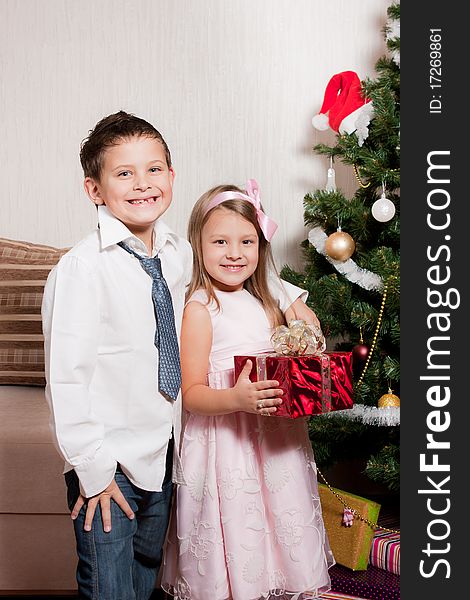 Merry girl and boy with gifts near a new-year tree. Merry girl and boy with gifts near a new-year tree