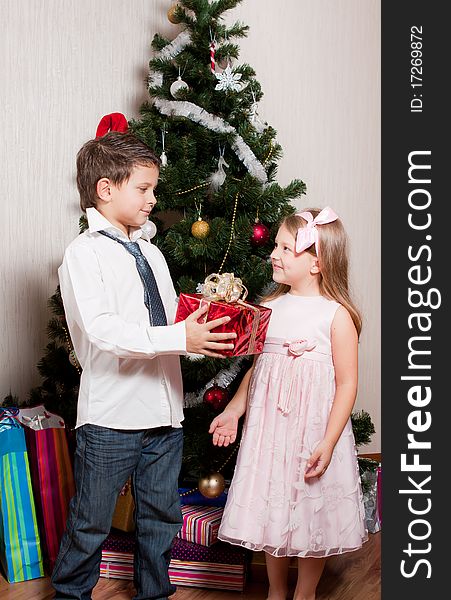 Merry girl and boy with gifts near a new-year tree. Merry girl and boy with gifts near a new-year tree