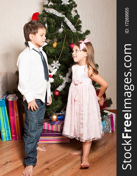 Merry girl and boy with gifts near a new-year tree. Merry girl and boy with gifts near a new-year tree