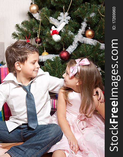 Merry girl and boy with gifts near a new-year tree. Merry girl and boy with gifts near a new-year tree