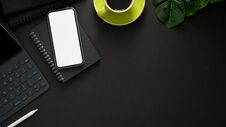 Top View Of Workplace With Wireless Keyboard, Mock Up Smartphone, Copy Space, Office Supplies And Coffee Cup On Black Table Royalty Free Stock Image