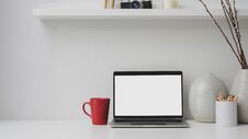 Cropped Shot Of Workplace With Blank Screen Laptop, Red Coffee Cup, Decorations On White Desk Royalty Free Stock Image