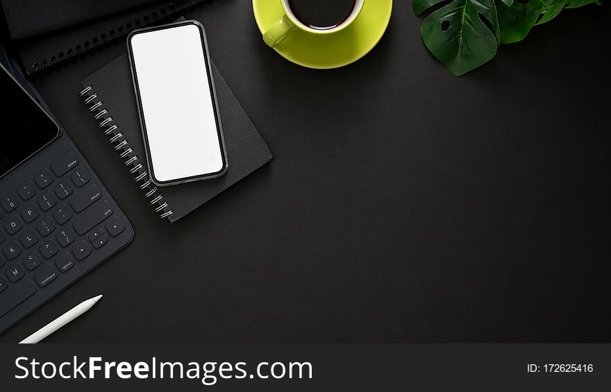 Top View Of Workplace With Wireless Keyboard, Mock Up Smartphone, Copy Space, Office Supplies And Coffee Cup On Black Table