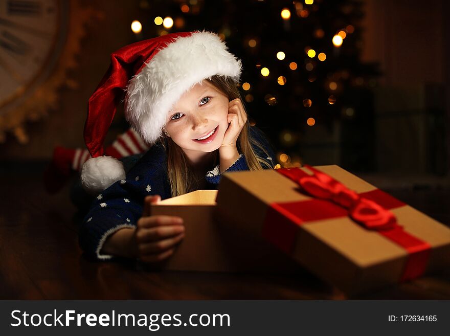 Cute child opening magic gift box near Christmas tree