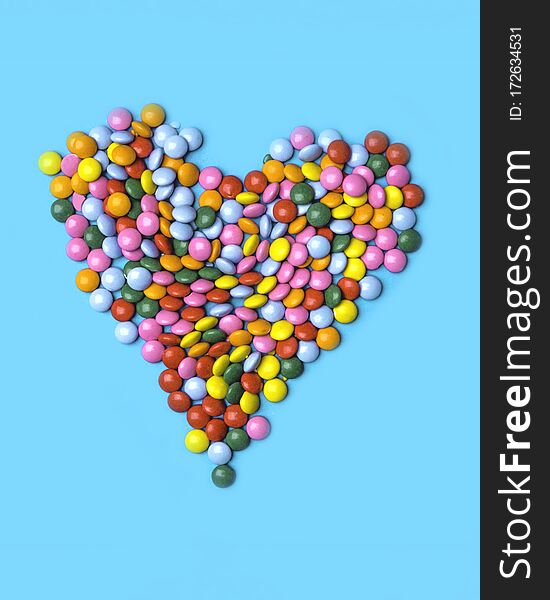 Colorful candies arranged as heart on blue background for valentines day, birthday, party card
