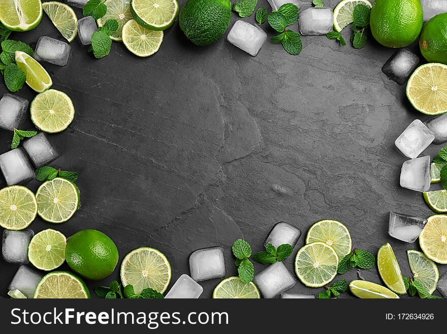 Frame made of lime slices, mint and ice on black table, top view with space for text. Lemonade layout