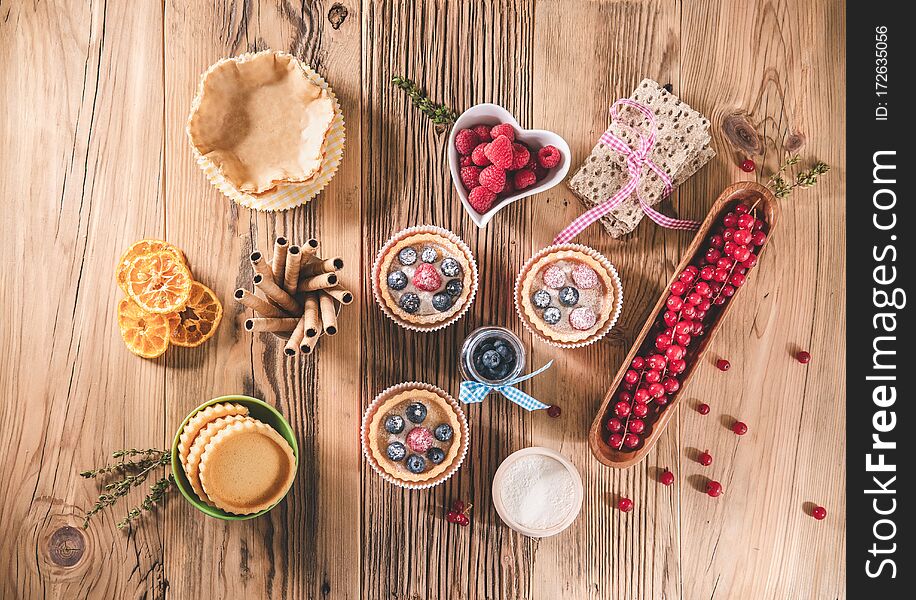 Delicious fresh blueberry and raspberries tartlets on wooden table. Retro concept