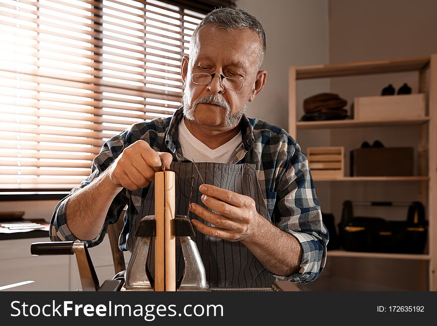 Man sewing piece of leather in workshop