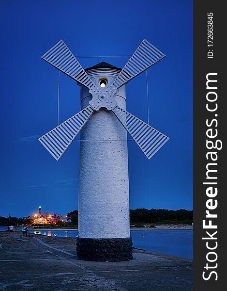 Lighthouse In The Evening On The Baltic Sea With Windmill Wings In SwinemÃ¼nde. Swinoujscie, Poland