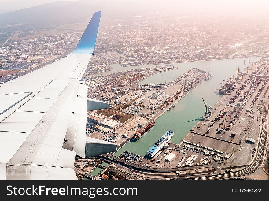 Airplane wing with view of industrial transport sea port