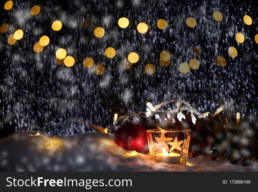 Christmas theme with candles, snow, pine cone and christmas light with pokeh effect