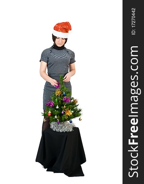 Young girl in the hat of Santa Claus dresses up Christmas tree