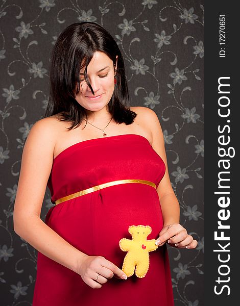 Beautiful pregnant woman with plush bear toy