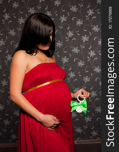Beautiful pregnant woman with little toy on grery background