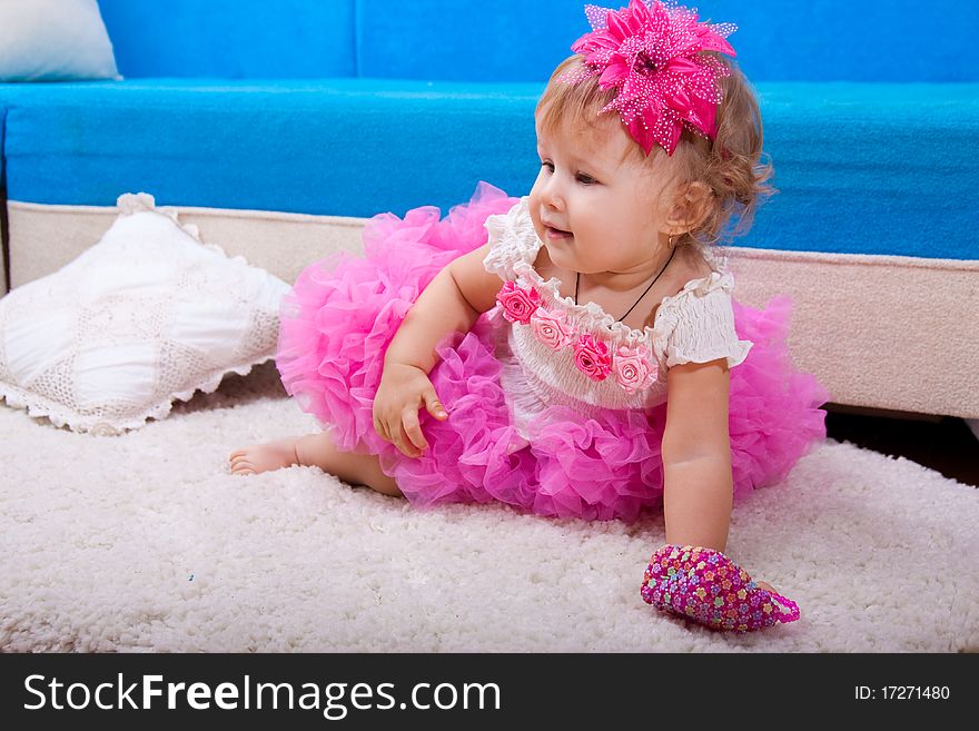 The nice little girl in a pink dress sits and smiles. The nice little girl in a pink dress sits and smiles