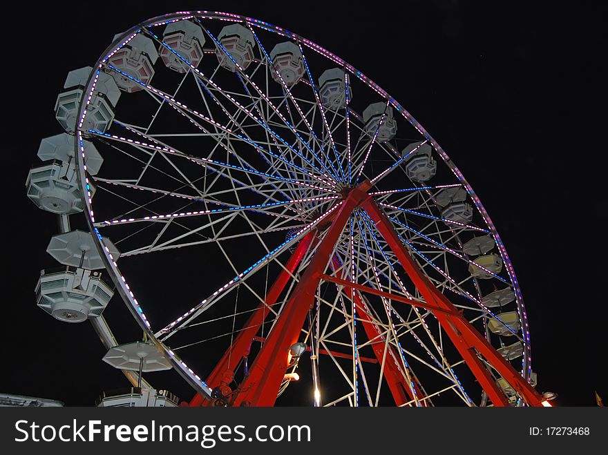 A ferris wheel at night lit with colorful neon lights