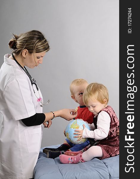 Young doctor communicating in hospital with baby boy and girl and preparing for examination. Young doctor communicating in hospital with baby boy and girl and preparing for examination