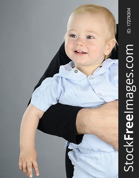 Beautiful baby boy posing in studio in parental hug. Beautiful baby boy posing in studio in parental hug