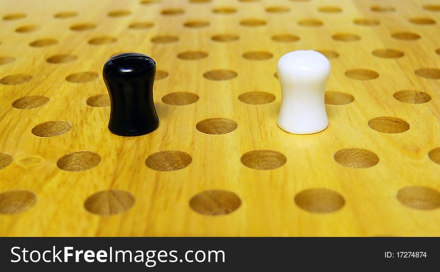 A black and a white peg on a chinese checkers board. A black and a white peg on a chinese checkers board
