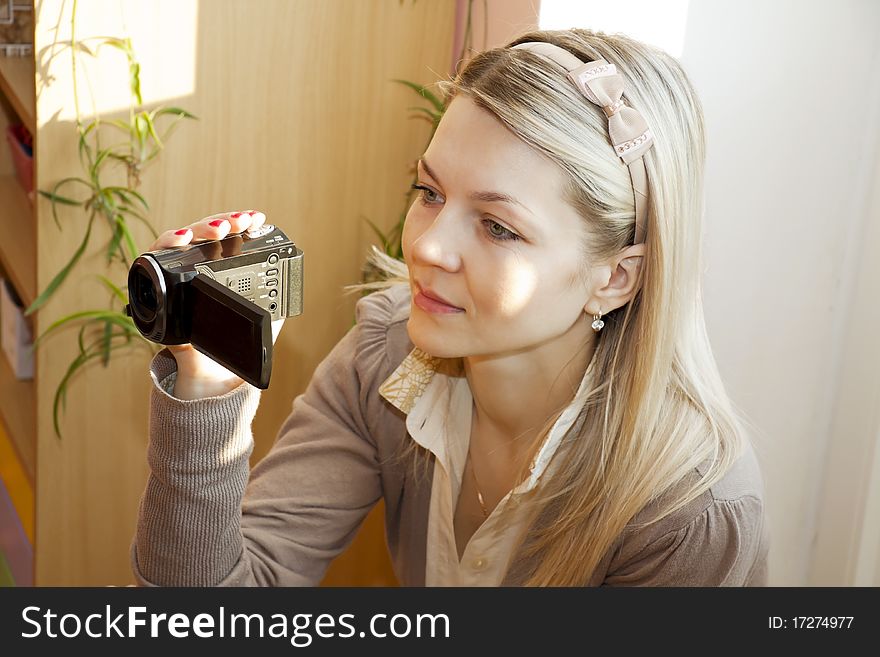 The woman holds a videocamera in a hand and with interest writes down. The woman holds a videocamera in a hand and with interest writes down