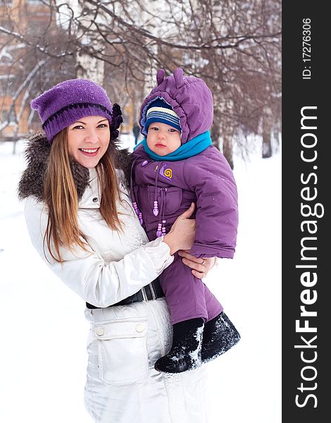 Mother holding a baby, snow, winter park, walk