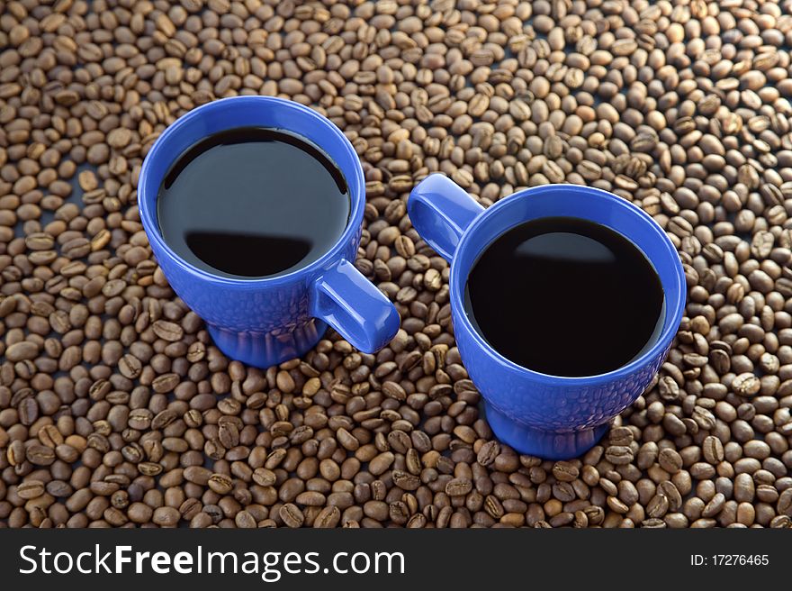 Coffee time - two mugs filled with hot coffe with smoke coffee beans and wood background. Coffee time - two mugs filled with hot coffe with smoke coffee beans and wood background