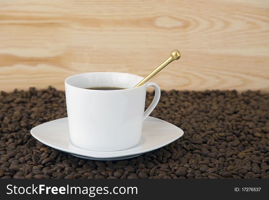 Coffee time - mug filled with hot coffe with smoke coffee beans and wood background. Coffee time - mug filled with hot coffe with smoke coffee beans and wood background