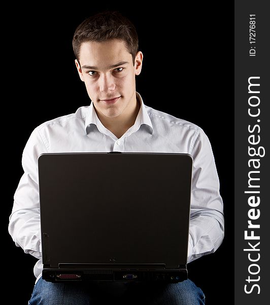 Young handsome man working on his laptop over black background. Young handsome man working on his laptop over black background.