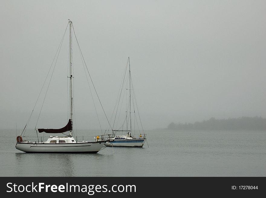 Two sail boats sit calmly on the misty lake with room for your text. Two sail boats sit calmly on the misty lake with room for your text