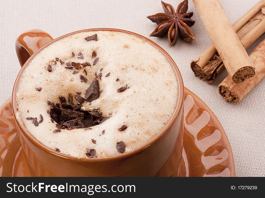 Cappuccino in a brown ceramic cup with spice.