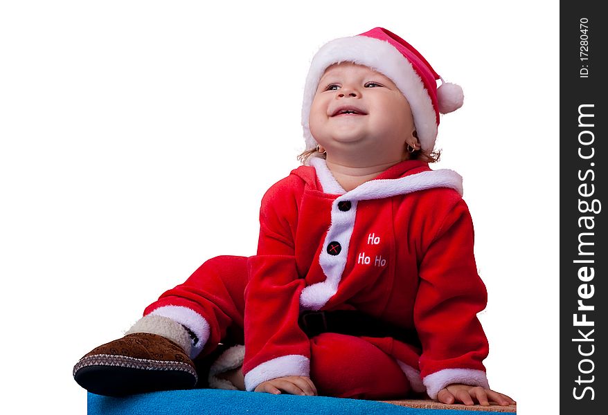 The wonderful kid with a naughty smile sits in a suit and a cap of Santa Claus. The wonderful kid with a naughty smile sits in a suit and a cap of Santa Claus