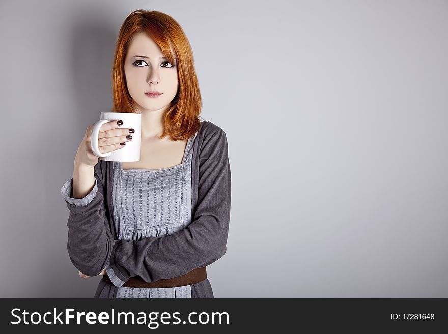 Portrait of red-haired girl with cup. Studio shot.