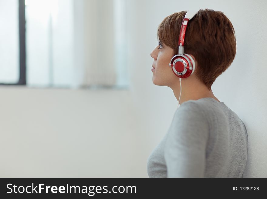 Young adult caucasian woman with headphones at home. Horizontal shape, side view, copy space. Young adult caucasian woman with headphones at home. Horizontal shape, side view, copy space