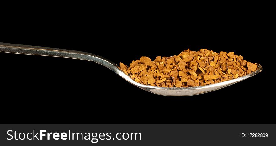 Instant coffee on a spoon isolated on black background