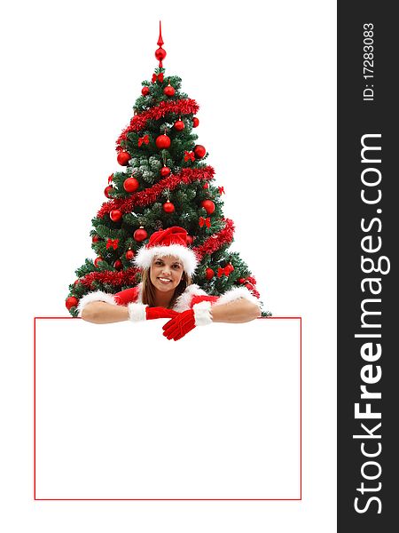 Female Santa with red hat and gloves, smiling over a white billboard near the Christmas tree. Female Santa with red hat and gloves, smiling over a white billboard near the Christmas tree