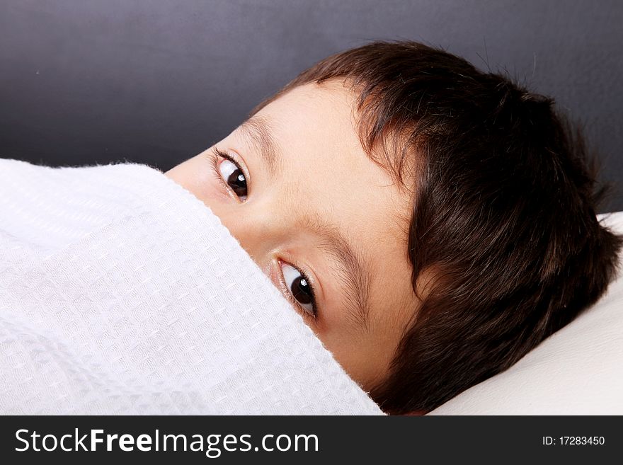 Child slept with the blanket in the face, looking at camera
