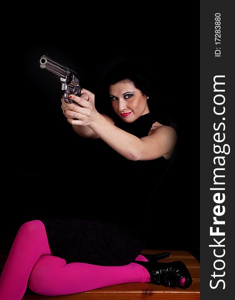 A woman wearing black and pink tights pointing a pistol at someone with a serious expression on her face. A woman wearing black and pink tights pointing a pistol at someone with a serious expression on her face.