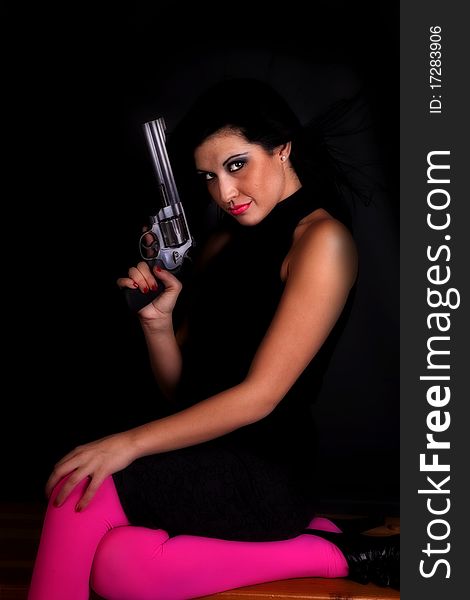 A woman in black and pink tights holding a pistol while she holds the gun up. A woman in black and pink tights holding a pistol while she holds the gun up.