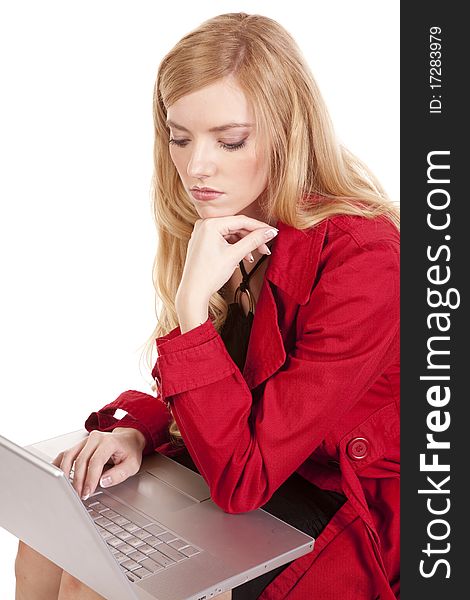 A woman in a red coat with a serious expression on her face looking at something on her computer. A woman in a red coat with a serious expression on her face looking at something on her computer.