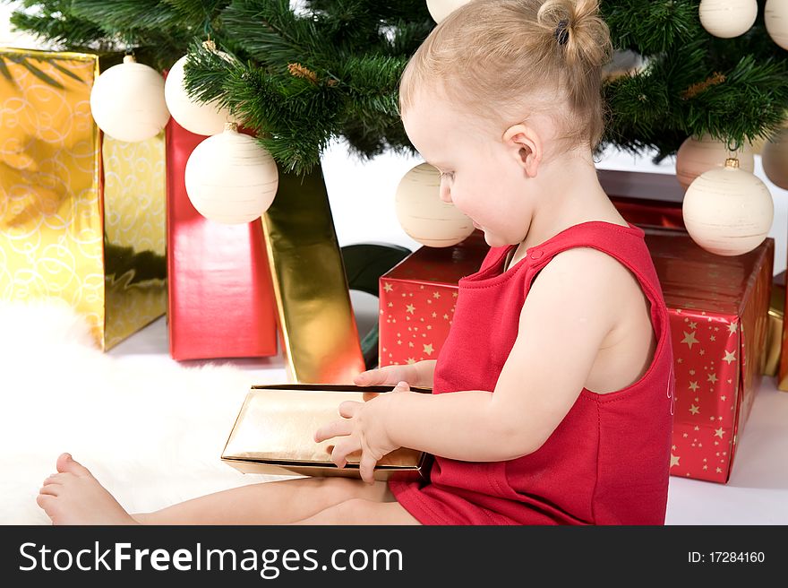 Little baby with gift under christmas tree. Little baby with gift under christmas tree