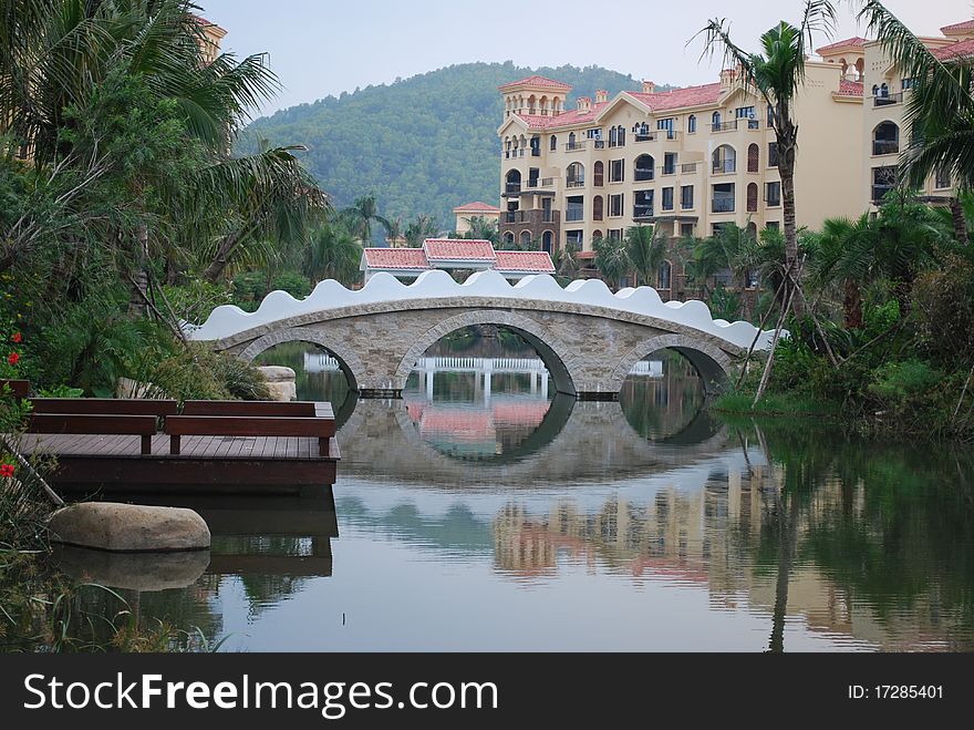 View of a beautiful bridge over a pond inside a tropical residential area. View of a beautiful bridge over a pond inside a tropical residential area